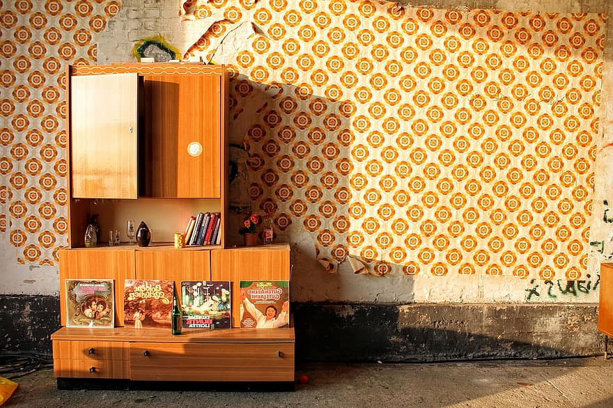 Obývací stěna z lakovaného dřeva před stěnou se vzorovanou retro tapetou